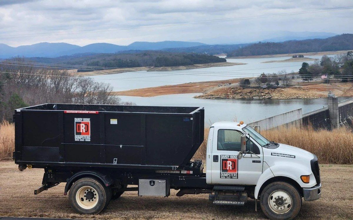 A Dandy Ridge Dumpsters truck hauling a roll-off dumpster above Douglas Lake near the dam in Jefferson County, TN.