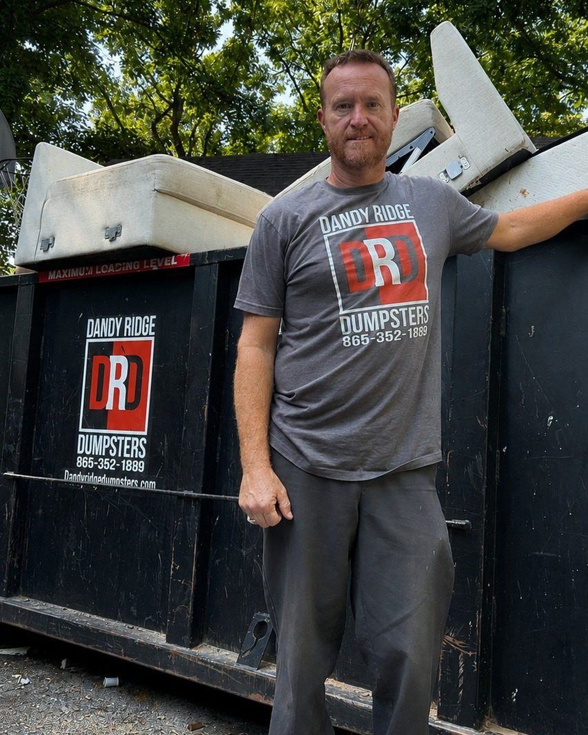 Jason Martin, owner of Dandy Ridge Dumpsters, by a branded roll-off dumpster in Jefferson County, TN.
